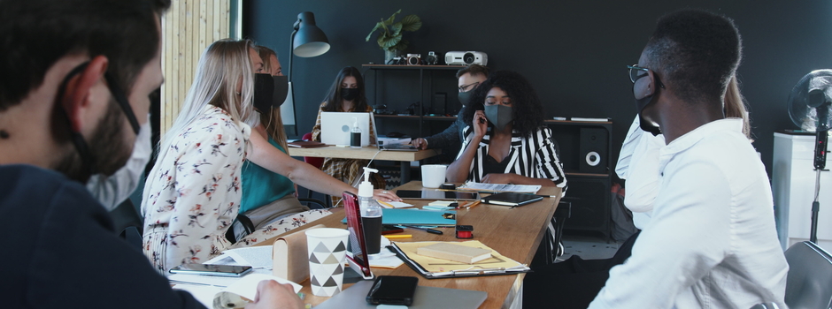 Office safety during COVID-19. Young multiethnic serious business people work together at meeting wearing face masks.