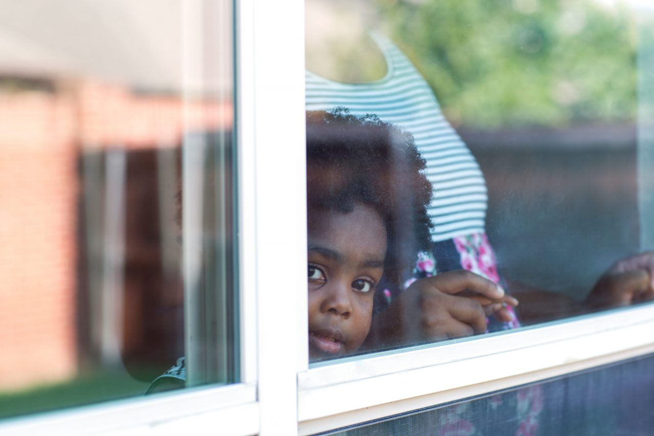 Young African American little girl looking out the window.