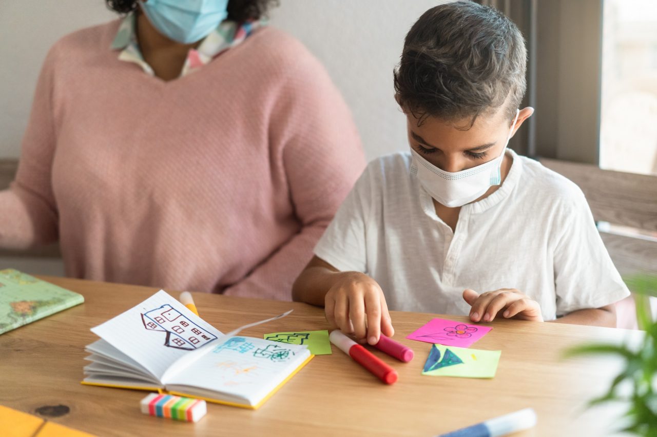 Child boy wearing safety mask in classroom while wearing safety